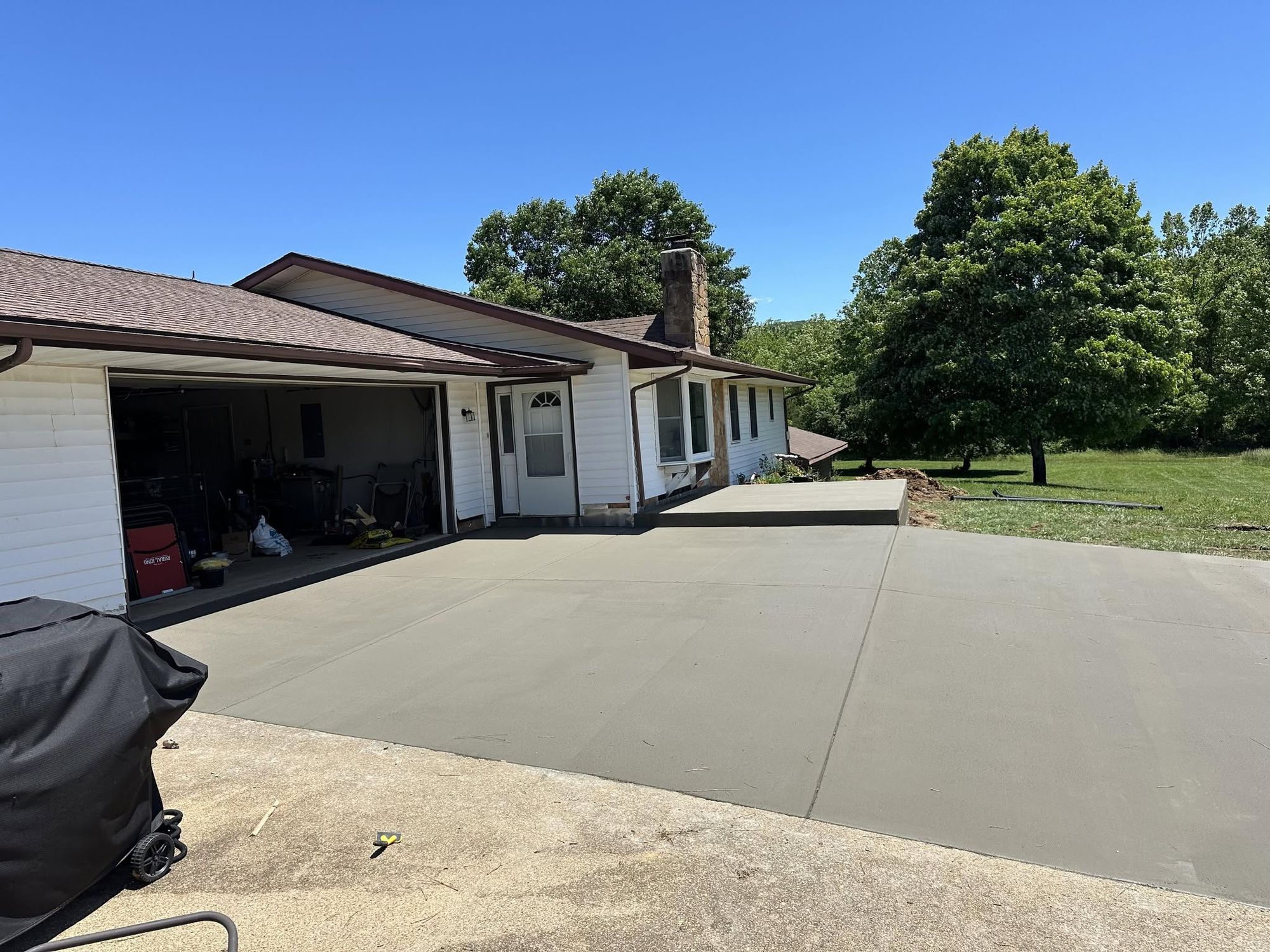 Finished concrete driveway and garage apron at a white ranch house