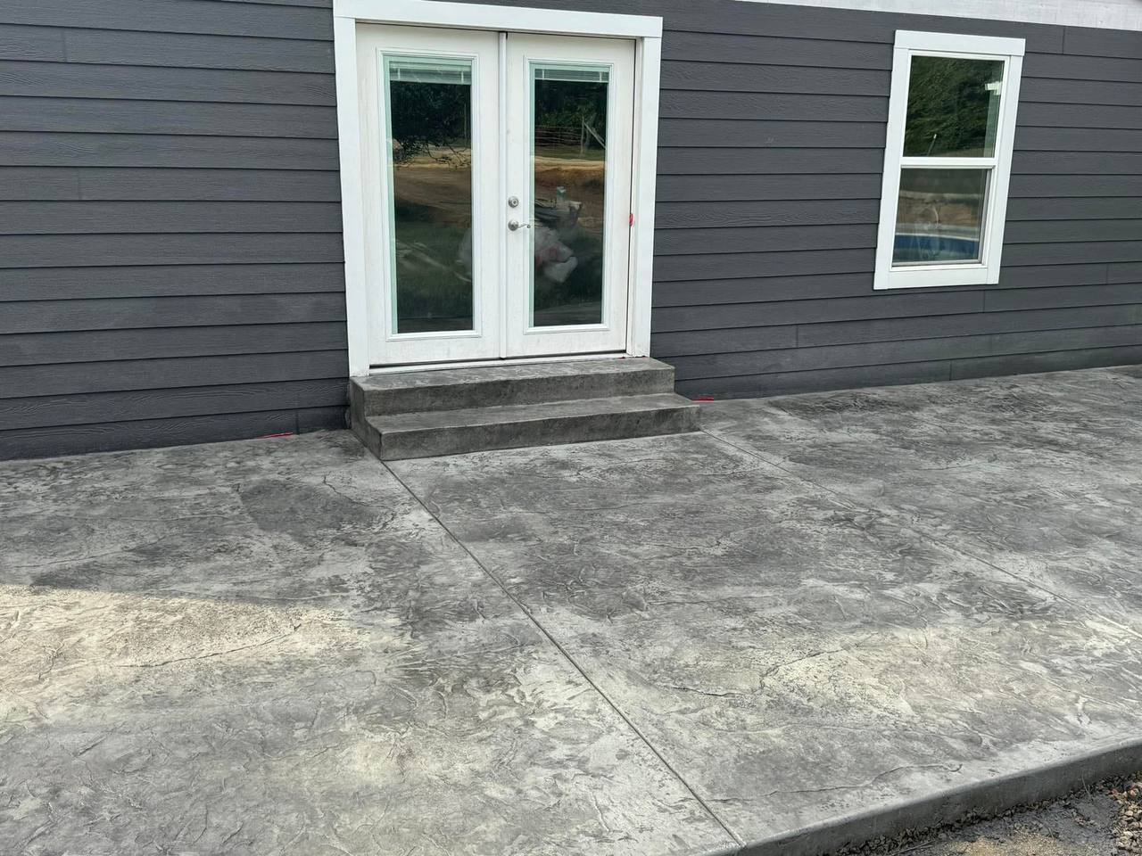 Stamped concrete patio and steps at a dark gray house