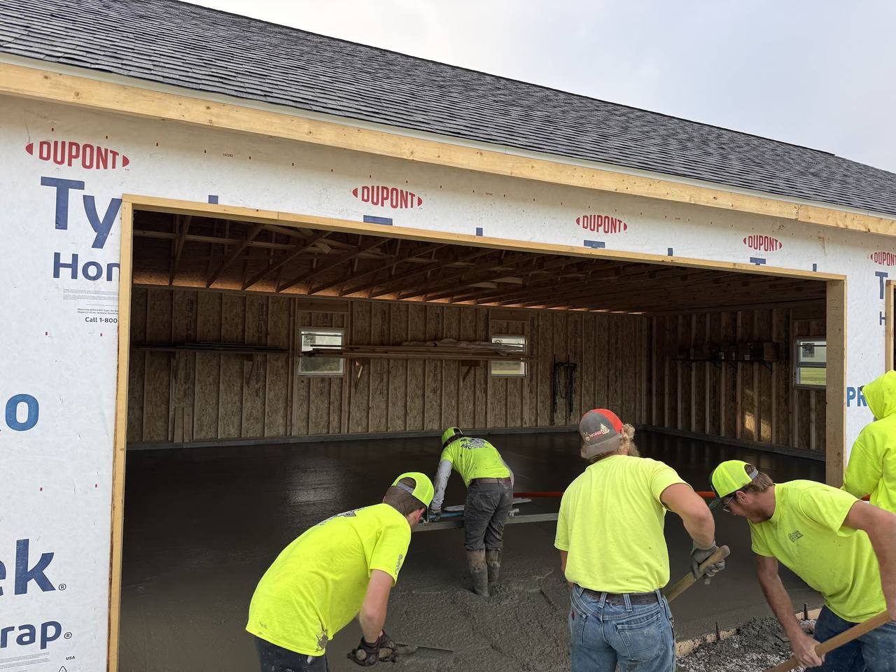 Crew finishing a fresh garage floor inside a framed garage